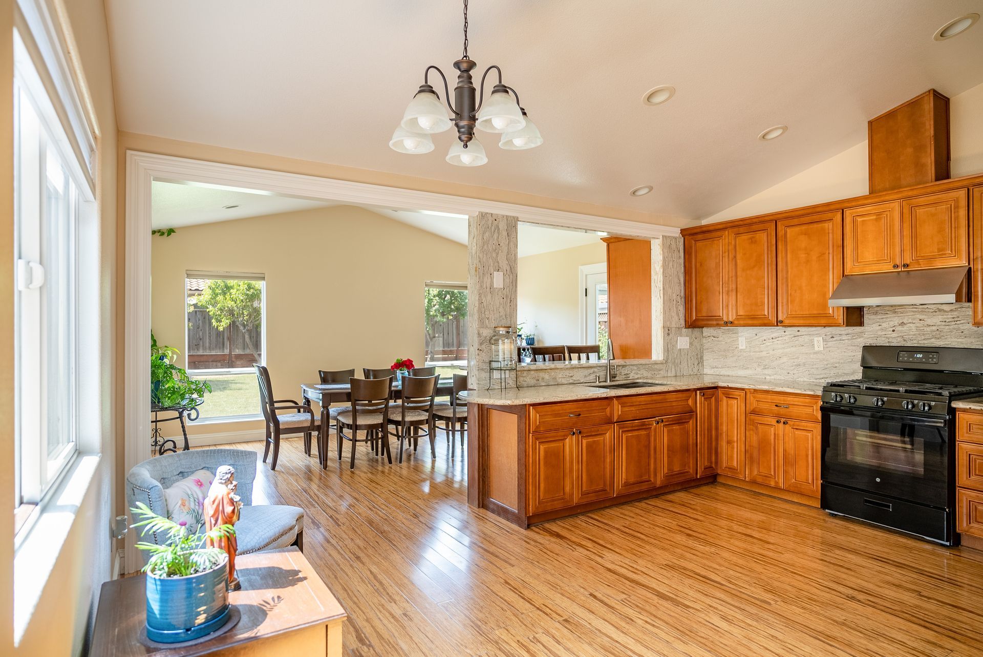 Kitchen with wooden cabinets, island, and dining area visible through an archway.