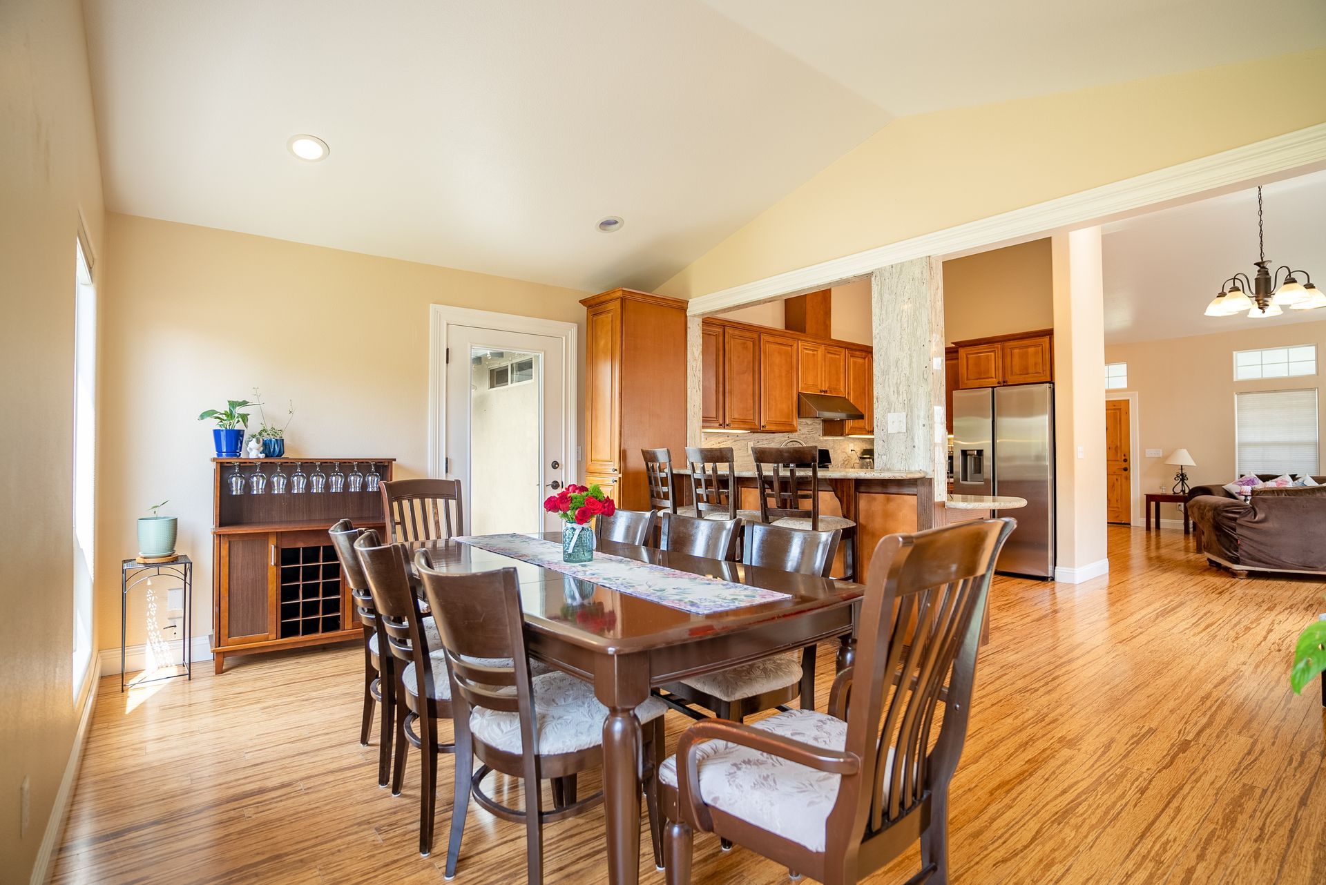 Dining room with wooden table, chairs, and view into kitchen and living room.