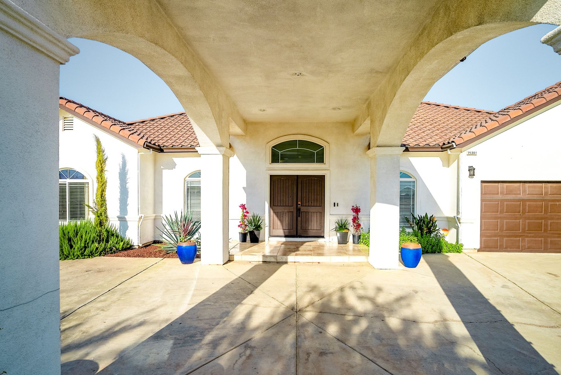 Exterior of a white stucco house with an arched portico over the front entrance.