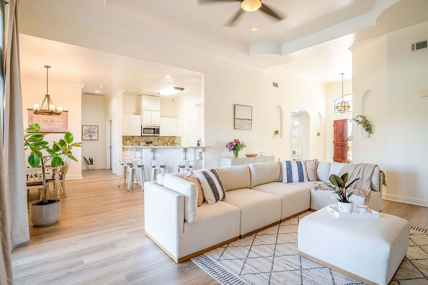 Spacious, bright living room with a white sectional, rug, and view to kitchen and dining area.