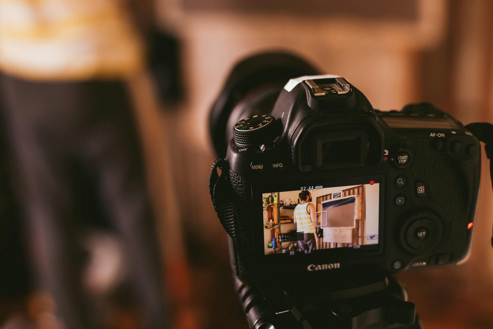 Black Canon DSLR camera recording a person indoors.