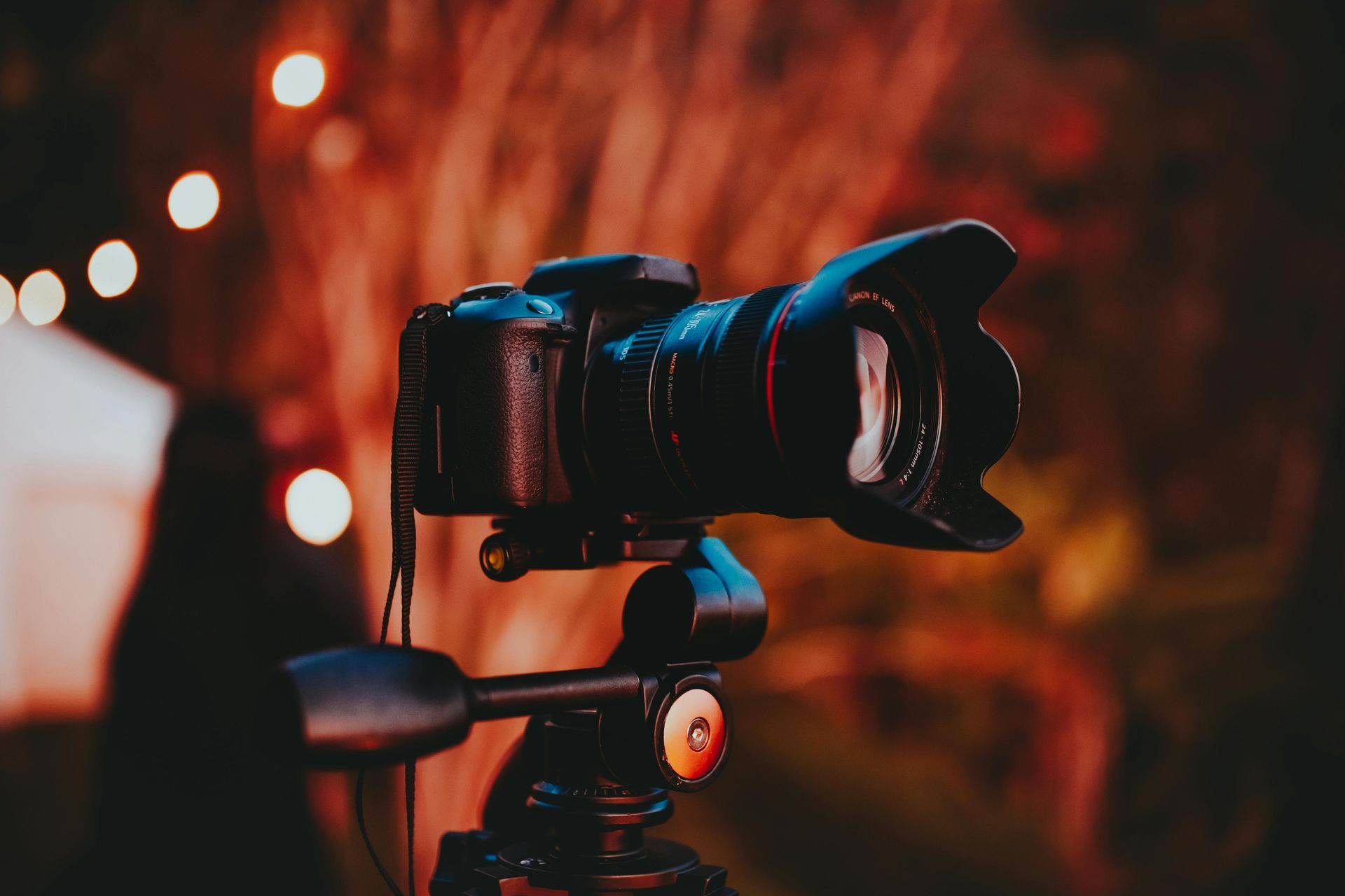 Camera on a tripod, outdoors at dusk. Bokeh background, warm lighting.