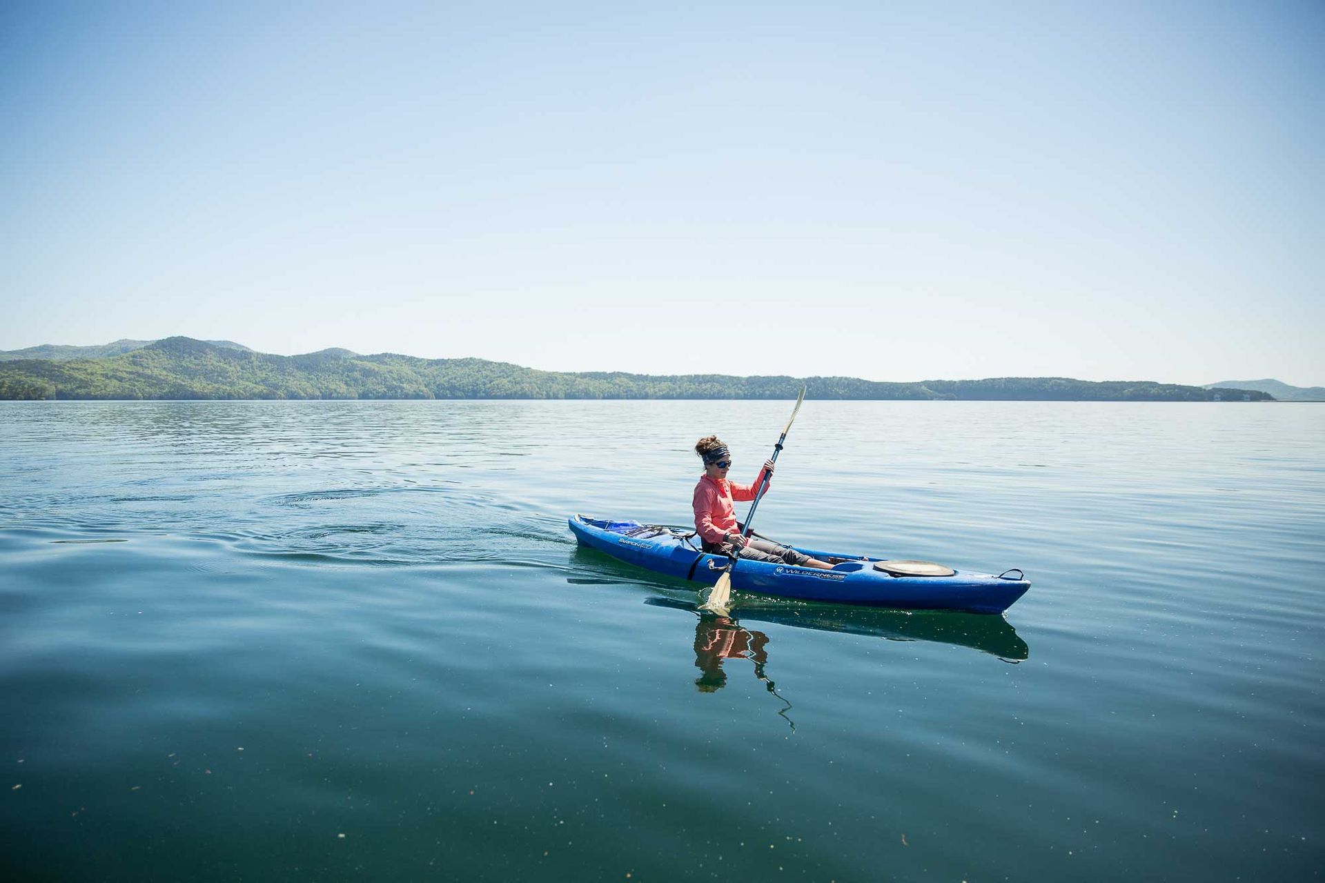 A woman kayaking on Lake Jocassee in Oconee County with the Jocassee Gorges behind her. Photo provided by Mac Stone.