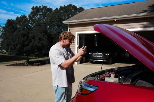 a person is holding a cell phone with a picture of a car on the screen .