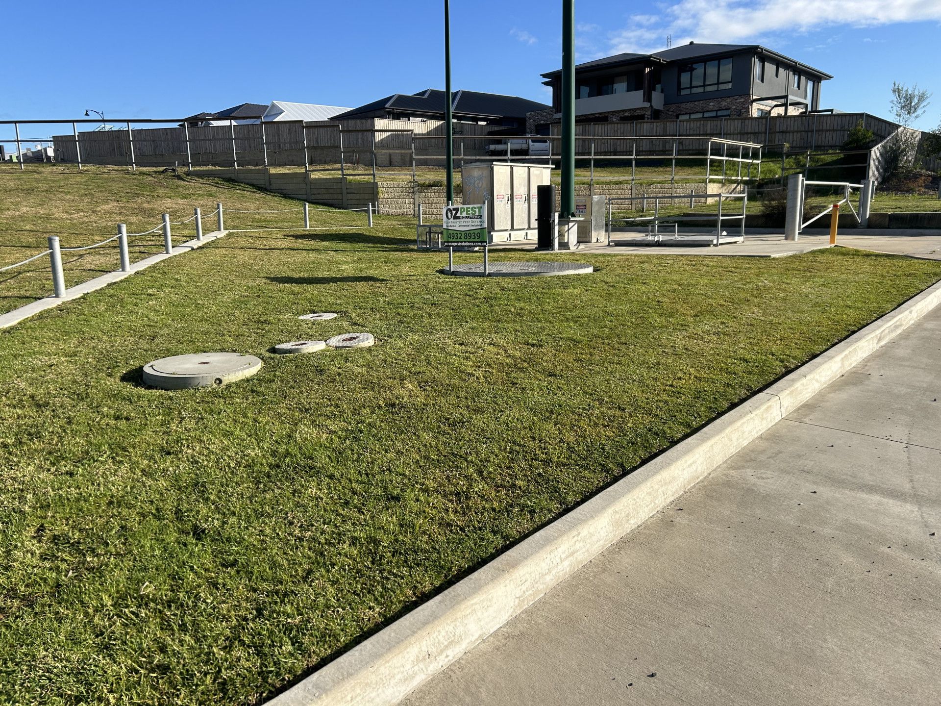 A lawn with a concrete curb and a house in the background