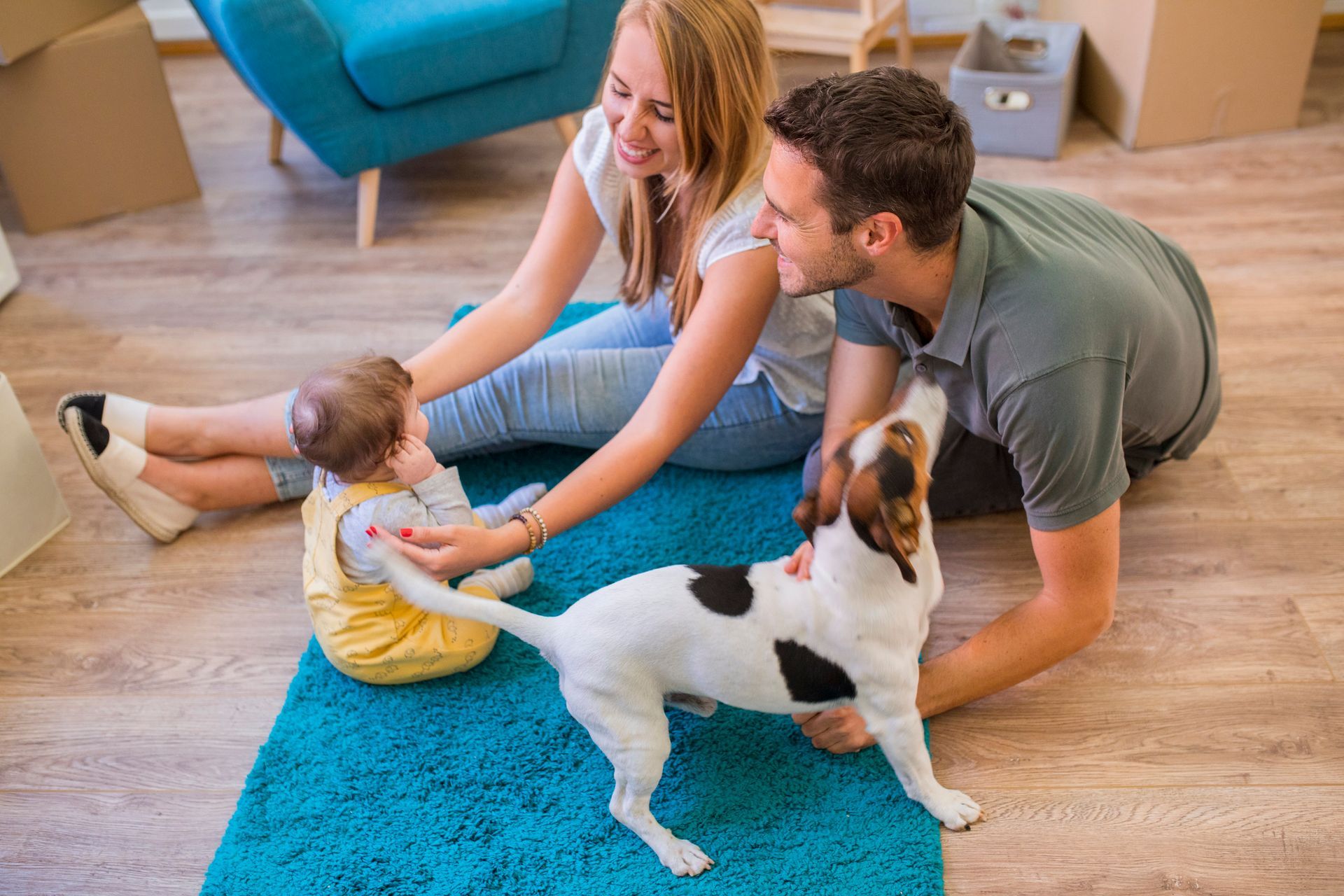 A man and woman are sitting on the floor with a baby and a dog.