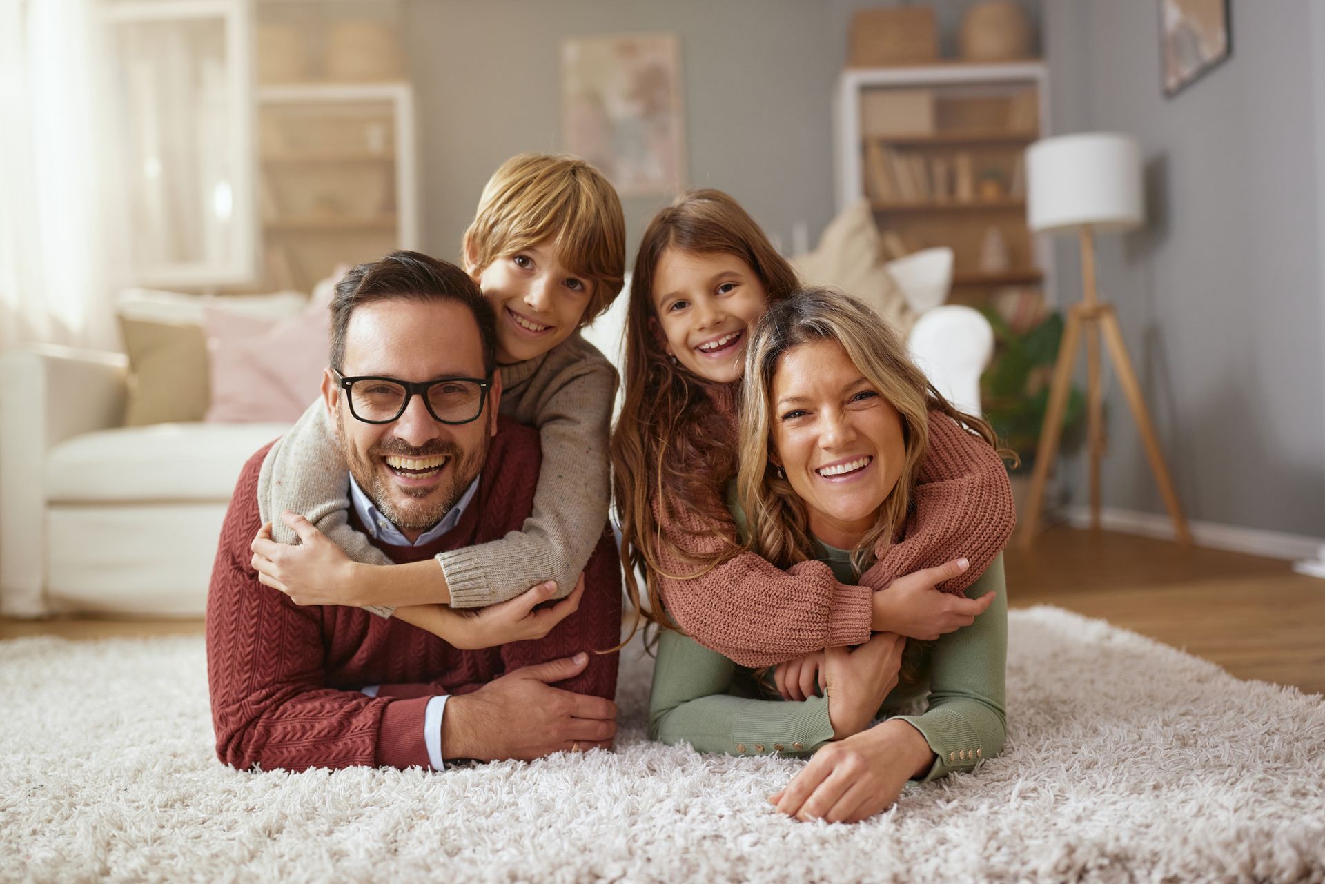A family is laying on the floor in a living room.