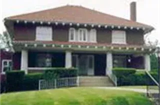 Two-story brick house with white trim, front porch, and green lawn