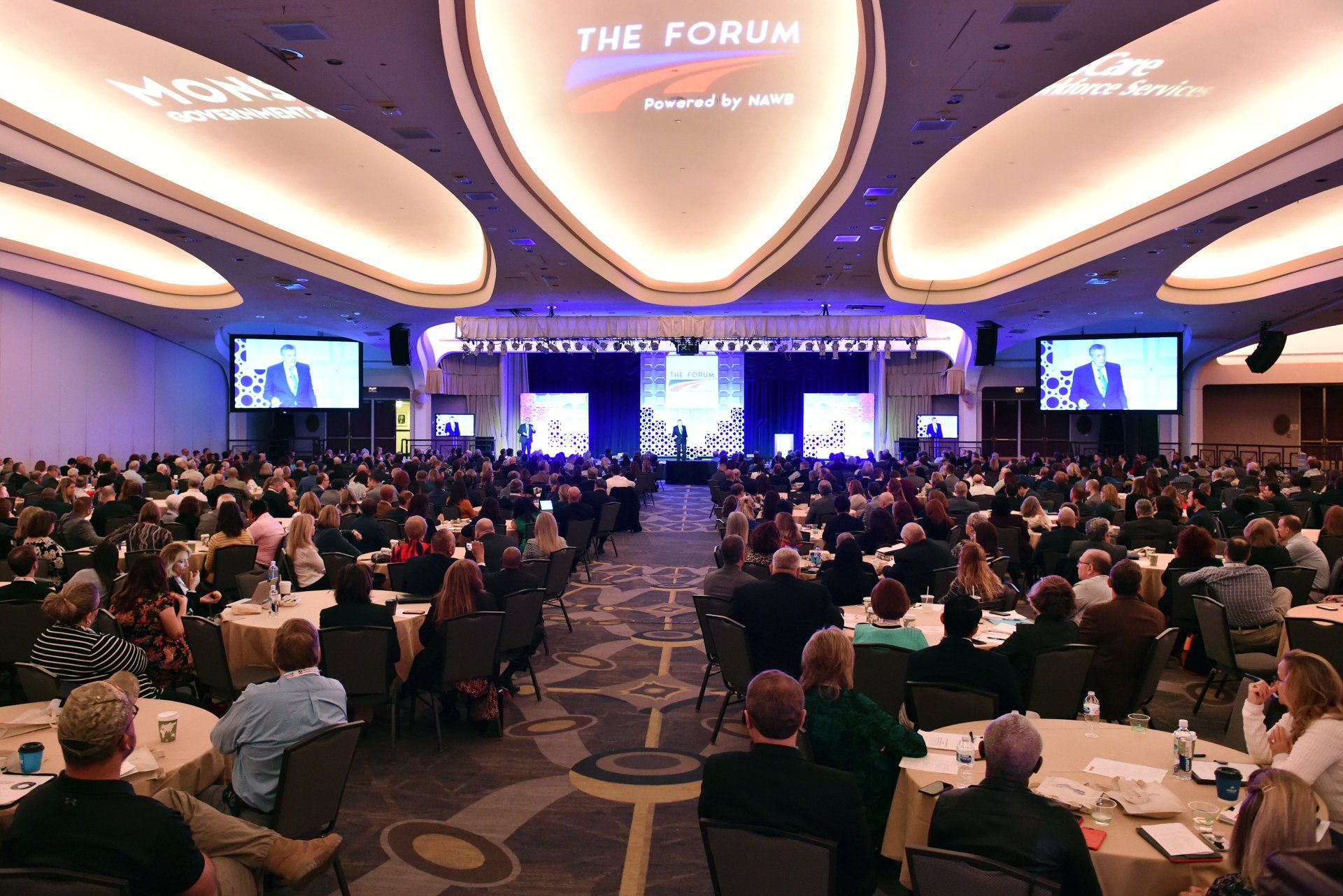 A large group of people are sitting at tables in a large room.