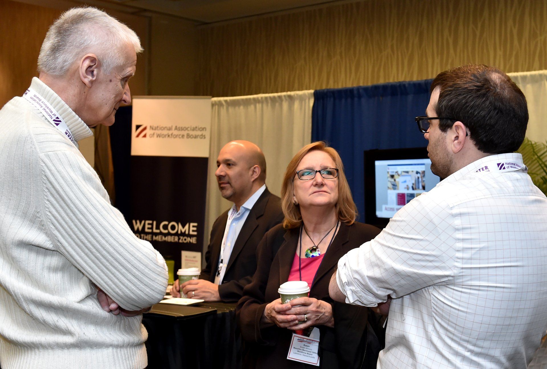 A group of people are standing around a table with a welcome sign in the background.