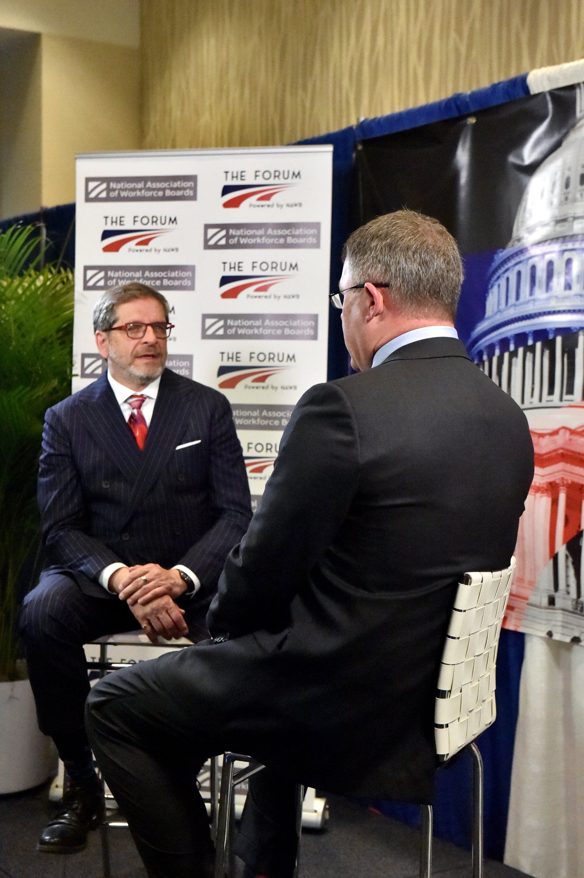 Two men in suits are sitting in front of a sign that says the forum