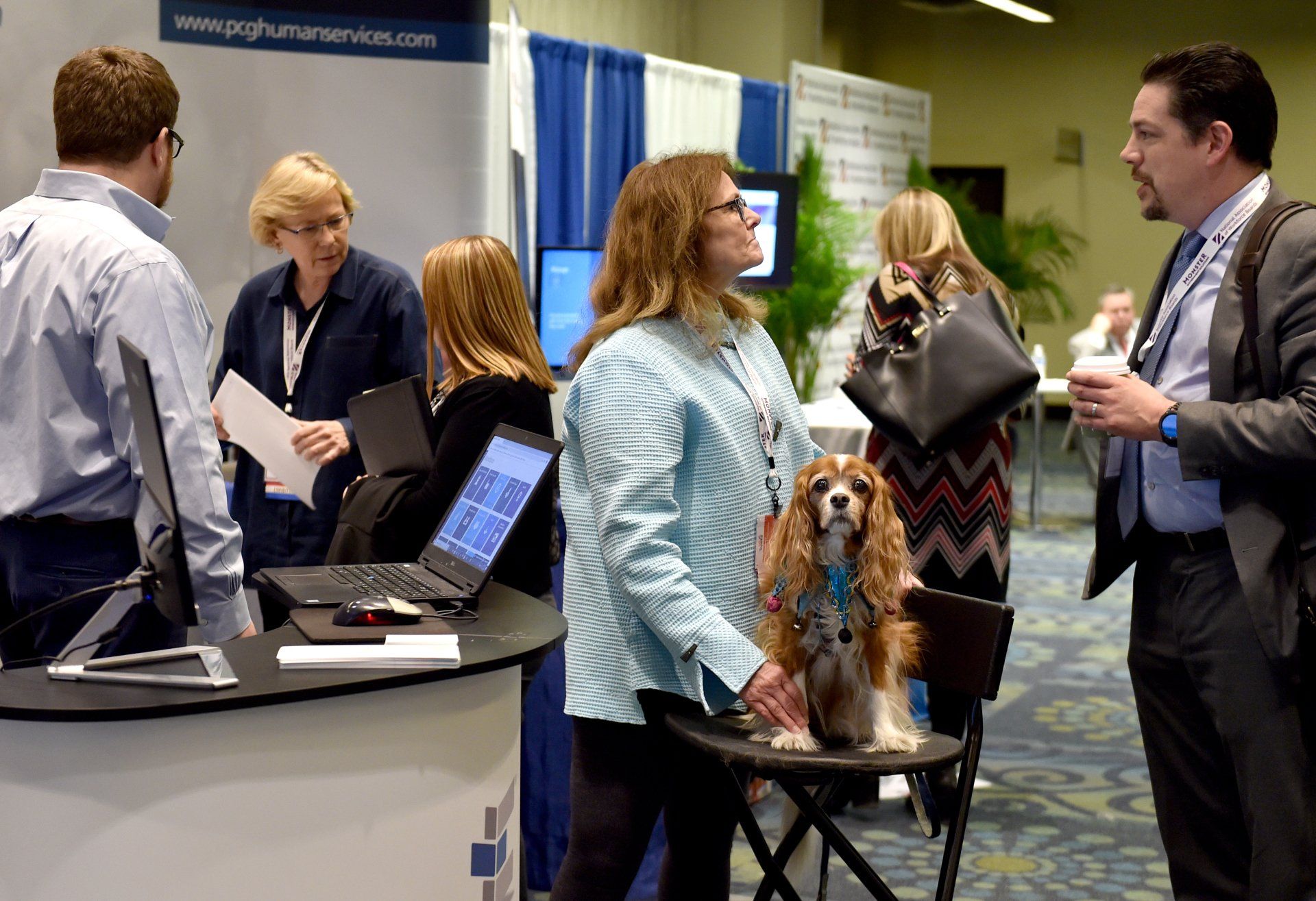 A woman is standing next to a dog at a job fair.