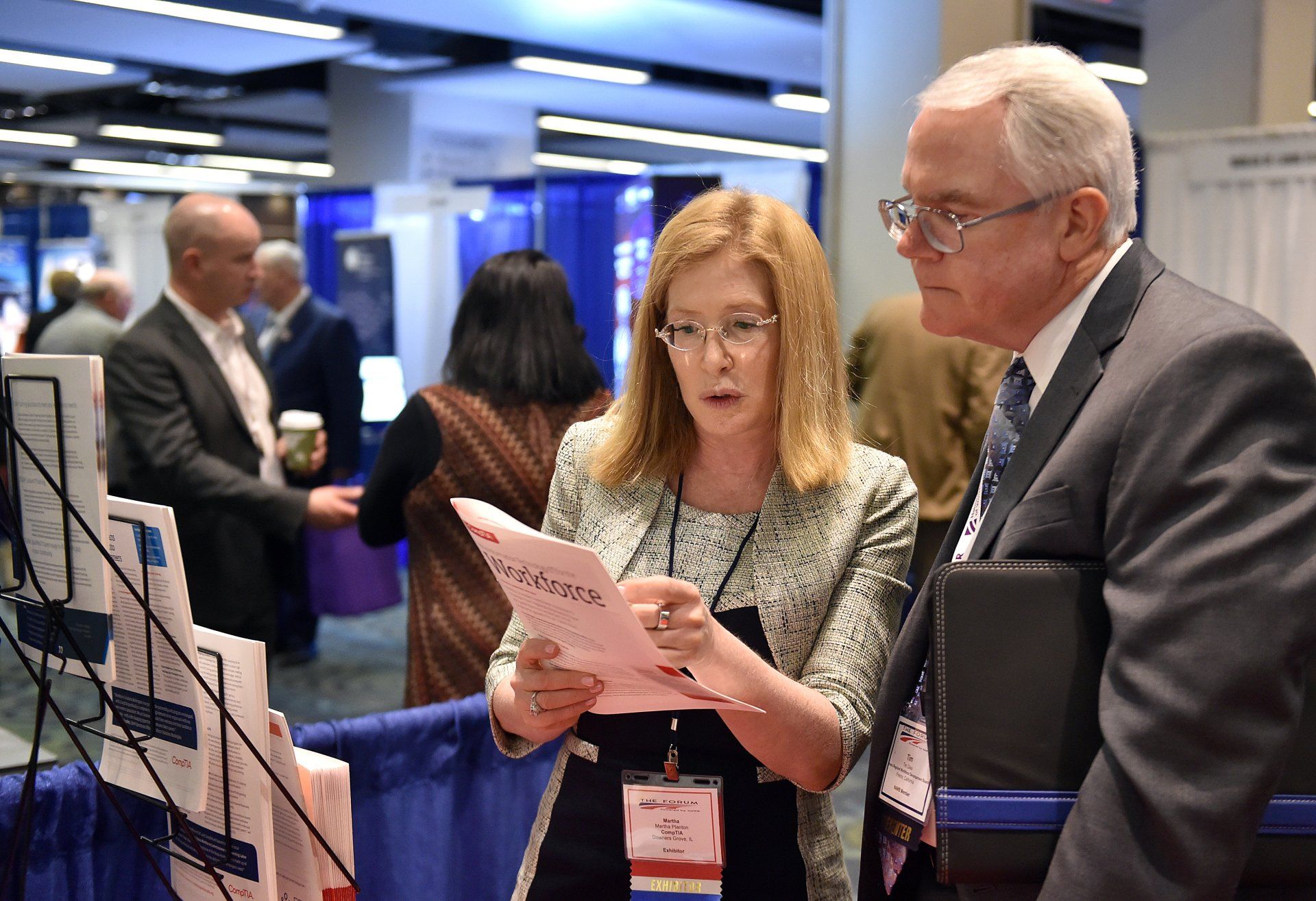 A man and a woman are looking at a pamphlet at a convention.