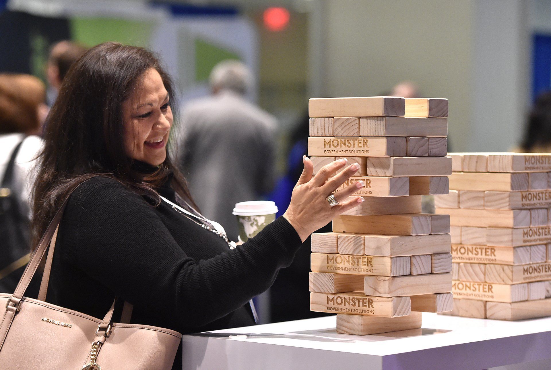 A woman is playing jenga with a stack of wooden blocks.