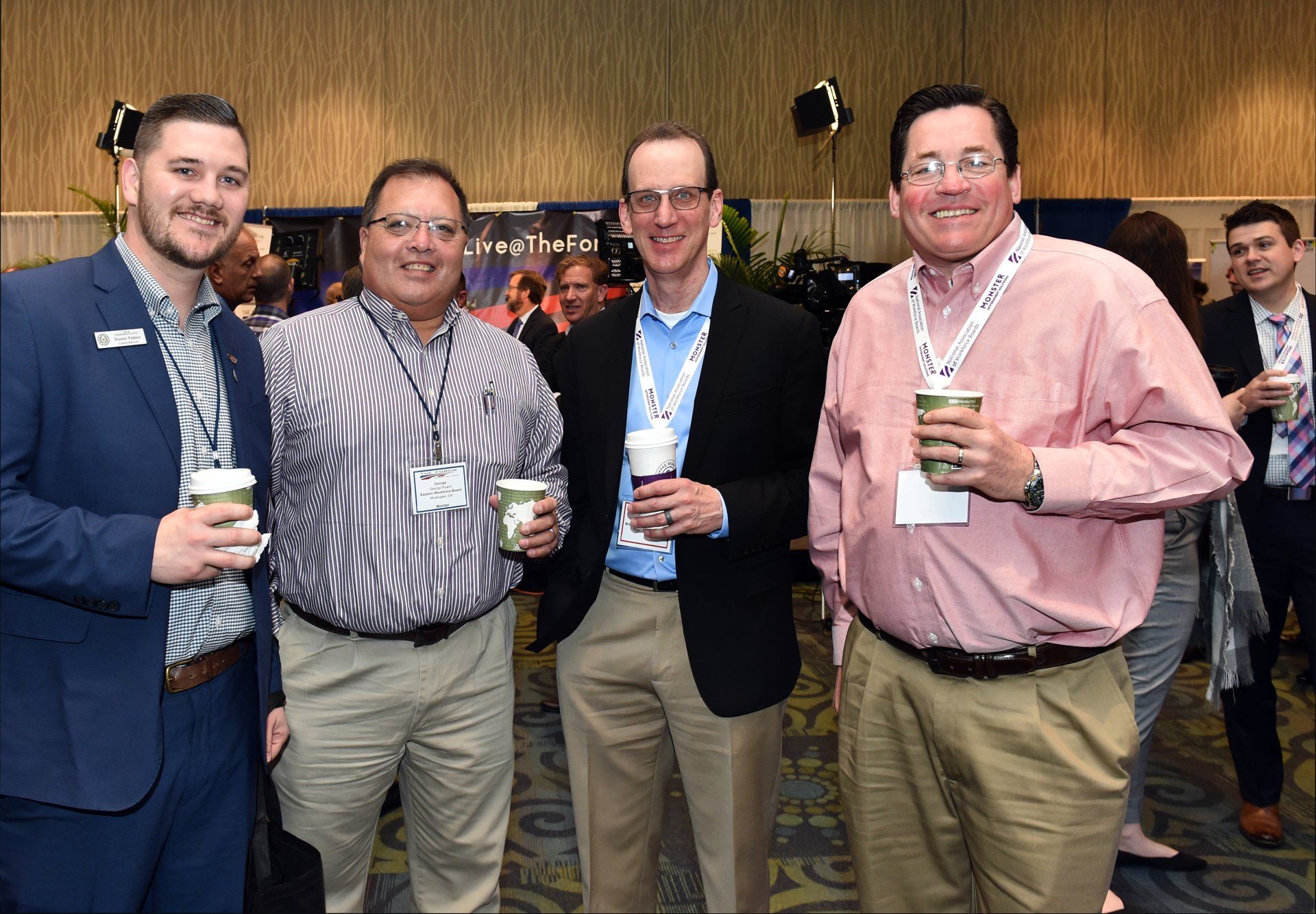 A group of men are standing next to each other holding cups of coffee.