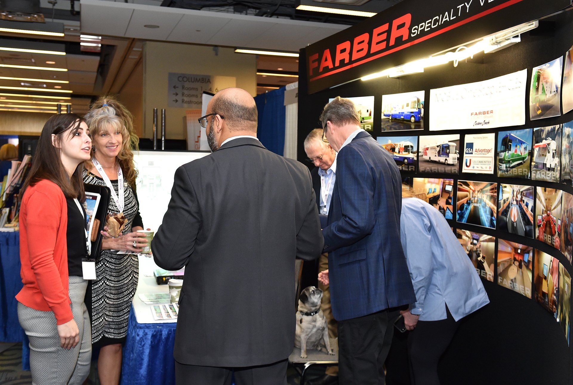 A group of people are standing around a booth at a convention.