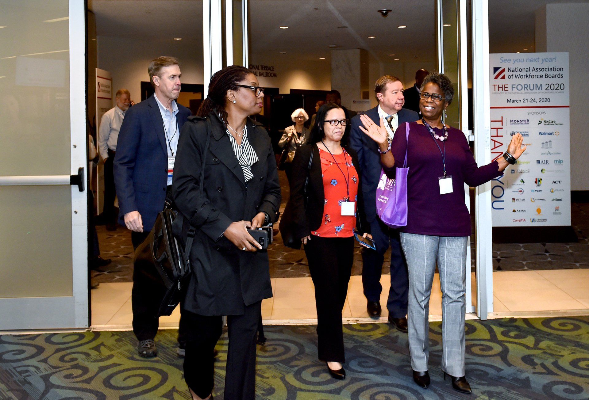 A group of people are walking out of a conference room