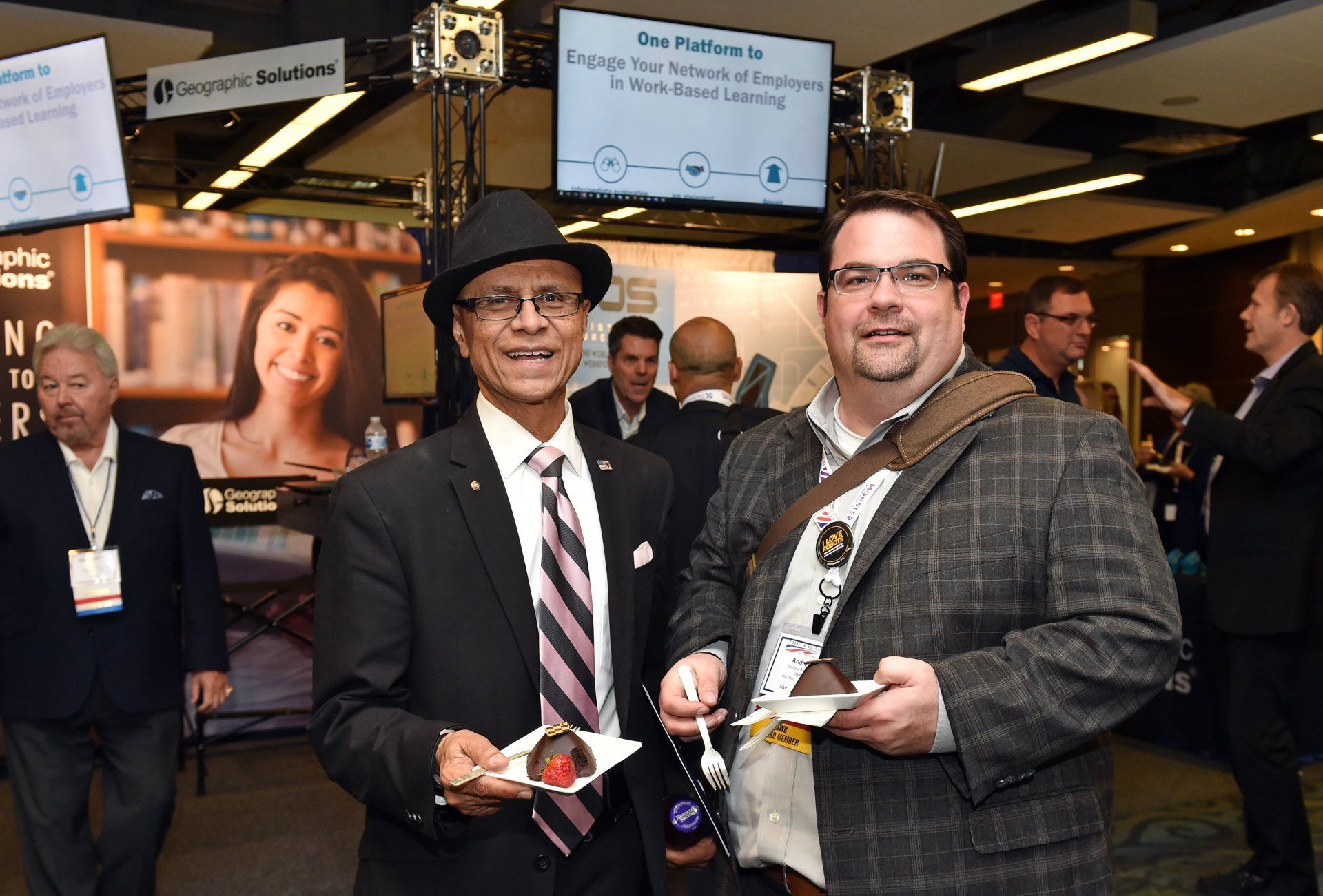 Two men in suits and hats are standing next to each other in a room.