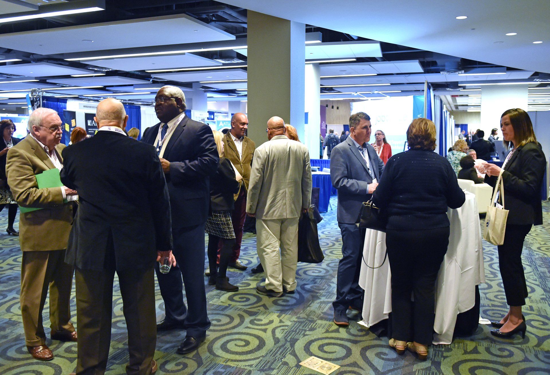 A group of people are standing in a room talking to each other.