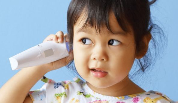 Sick girl taking her temperature using a thermometer