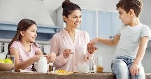 A woman and two children are sitting at a counter in a kitchen.