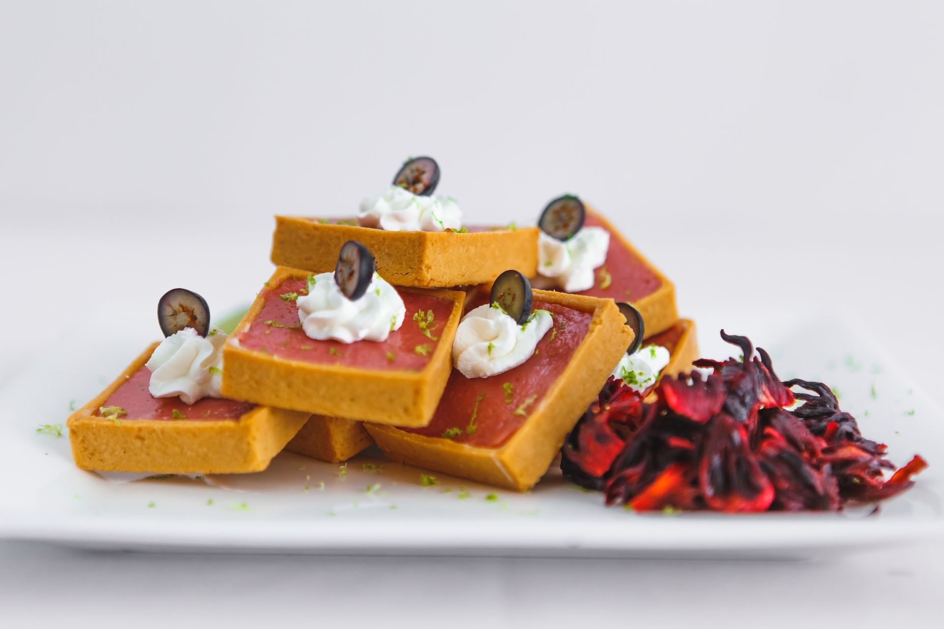 A row of flan desserts on a white plate on a table.