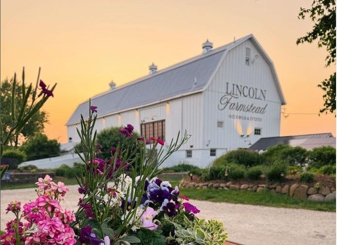 A large barn with a wooden floor and a chandelier hanging from the ceiling.