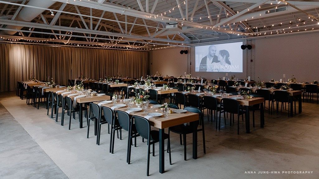 A large room filled with tables and chairs and a projector screen.