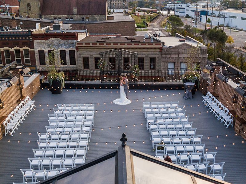 An aerial view of a wedding ceremony on a rooftop with rows of chairs.