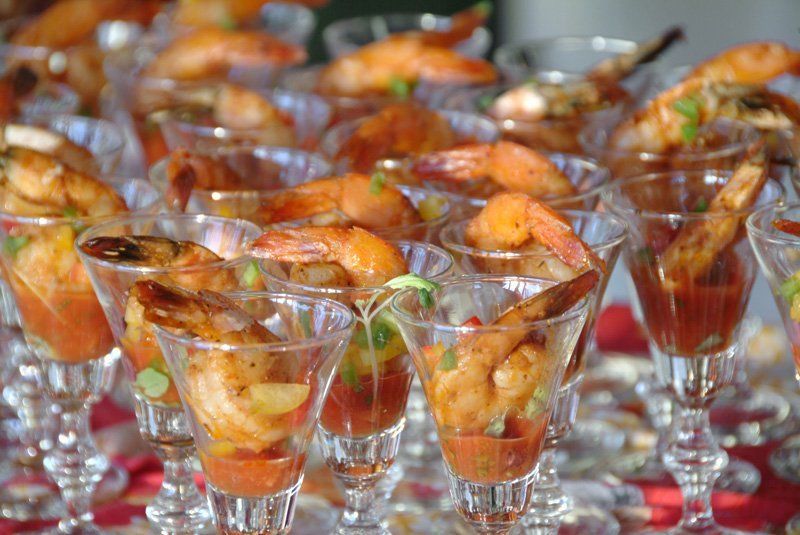 A row of martini glasses filled with shrimp and tomato sauce.