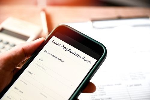 Hand holding smartphone displaying a loan application form.