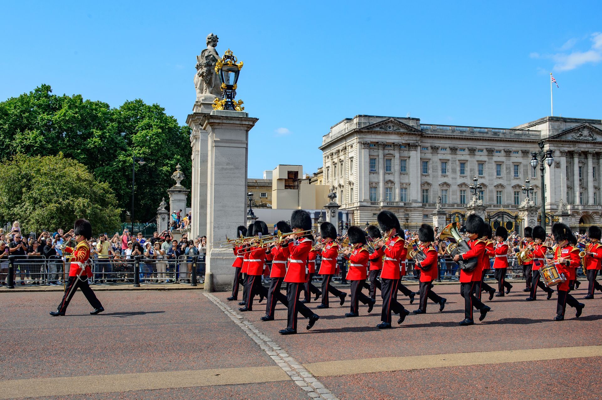 Changing of the Guard ceremony outside Buckingham Palace with marching guards and spectators
