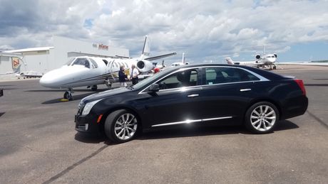 A black car is parked in front of an airplane