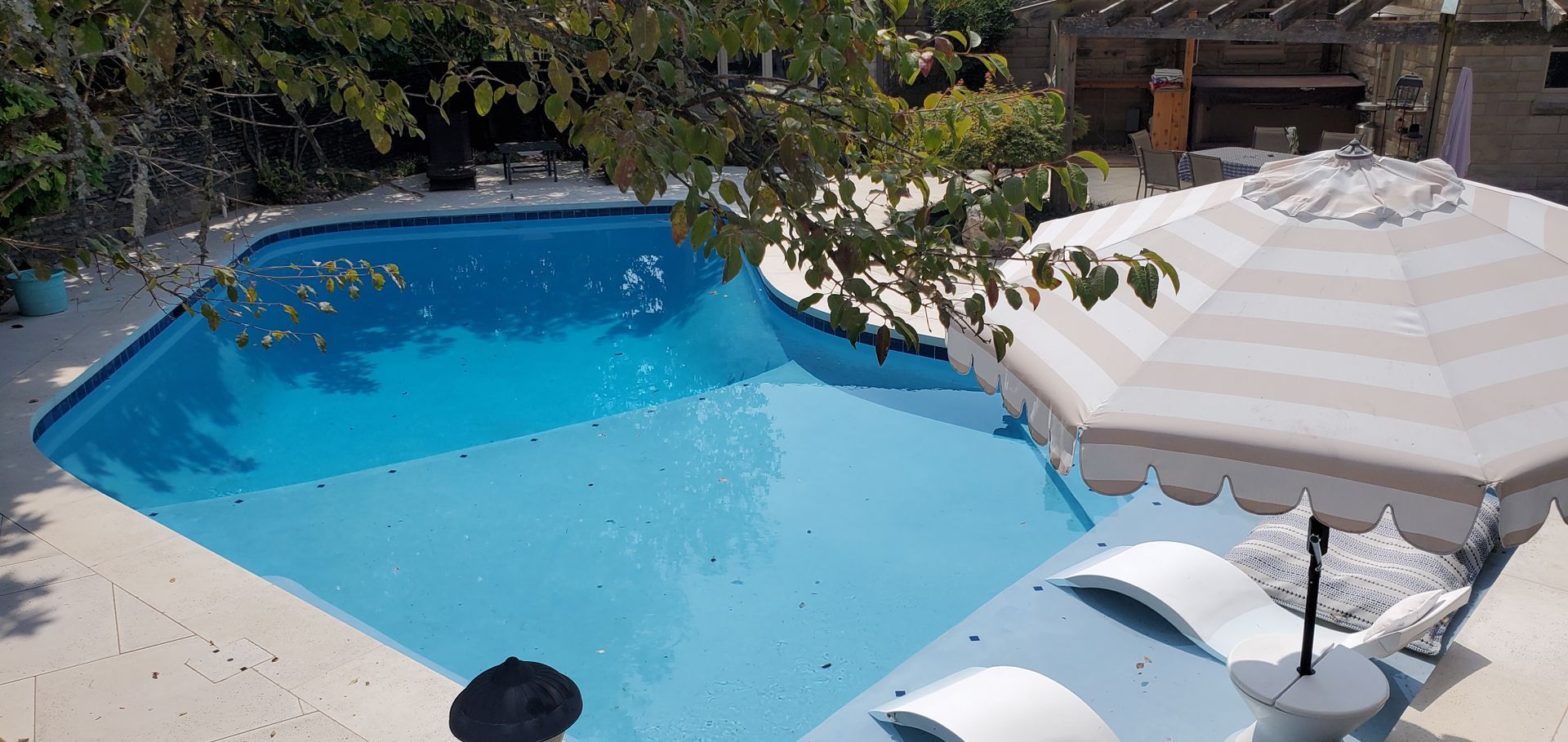 A large swimming pool with umbrellas and chairs around it.