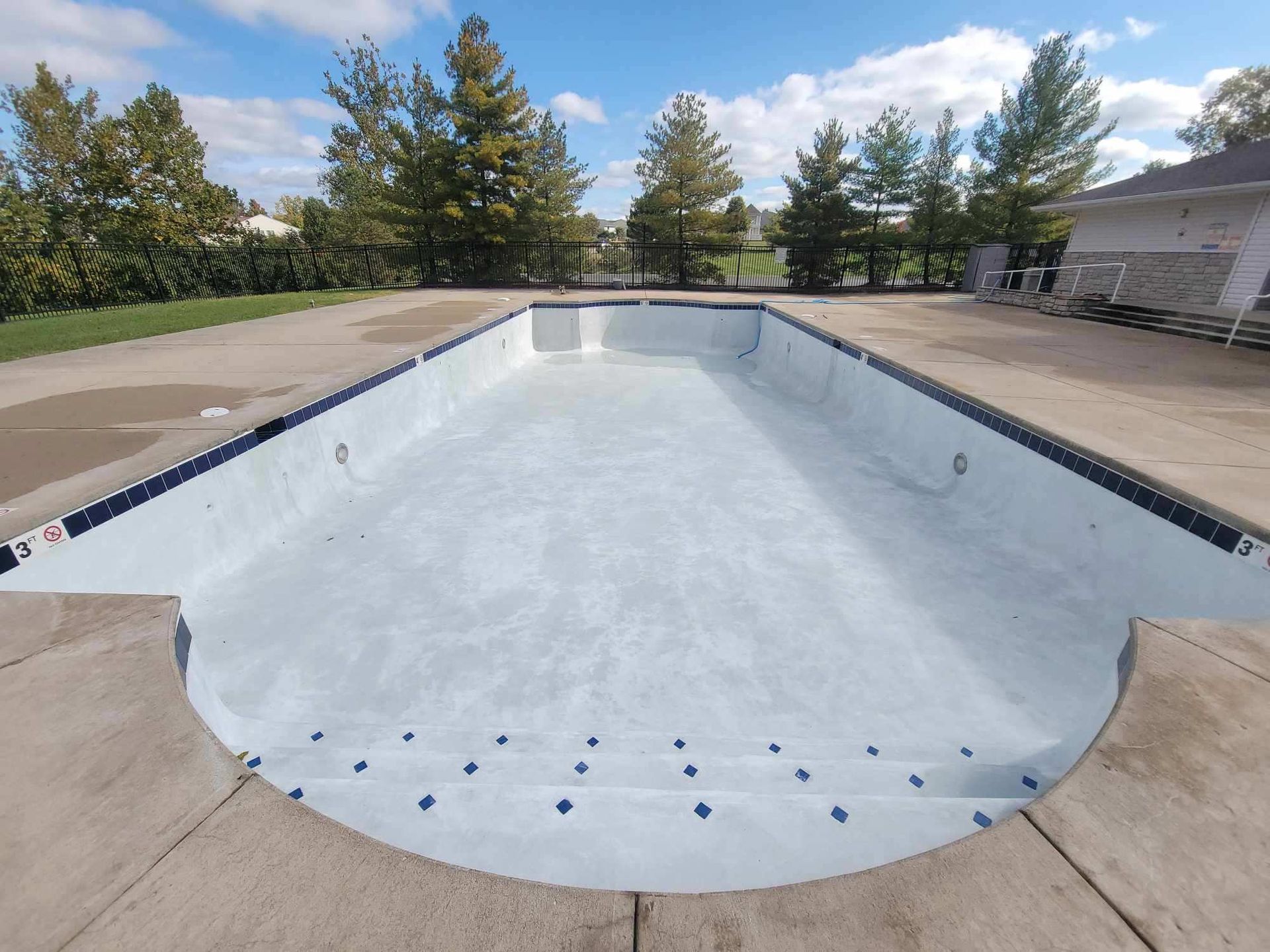 An empty swimming pool with trees in the background