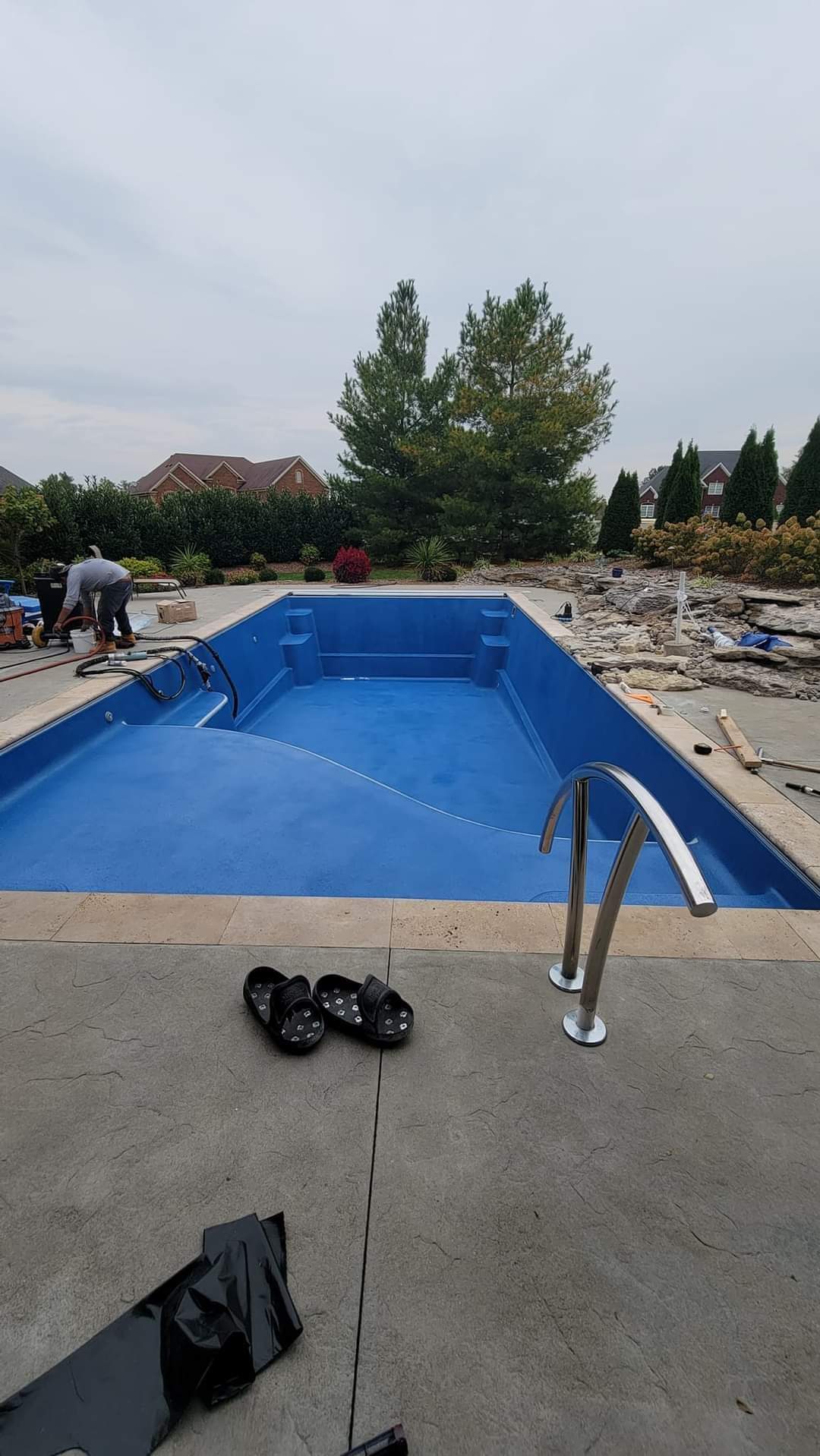 A large blue swimming pool is being built in a backyard.
