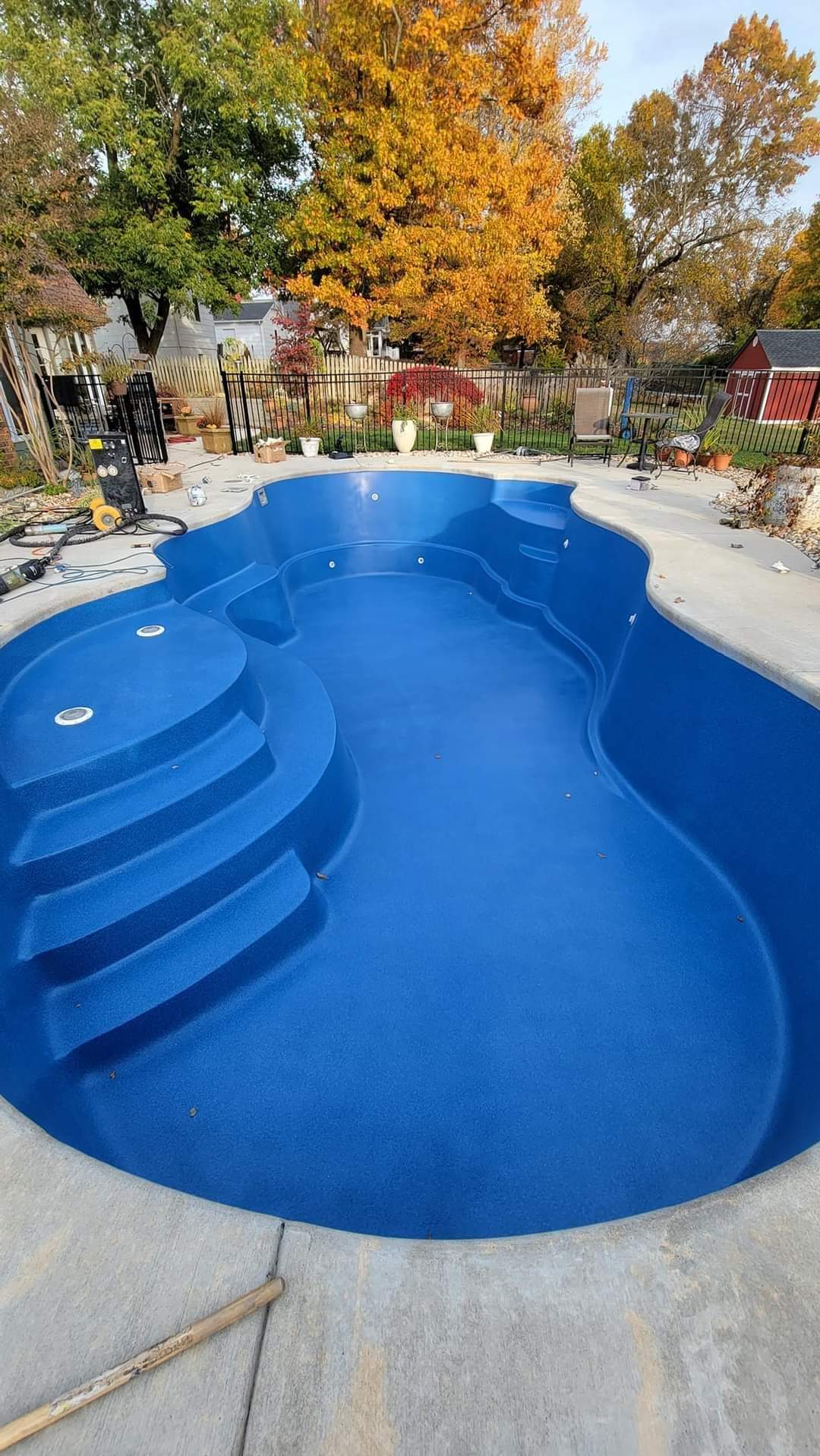 A large blue swimming pool with stairs and trees in the background.