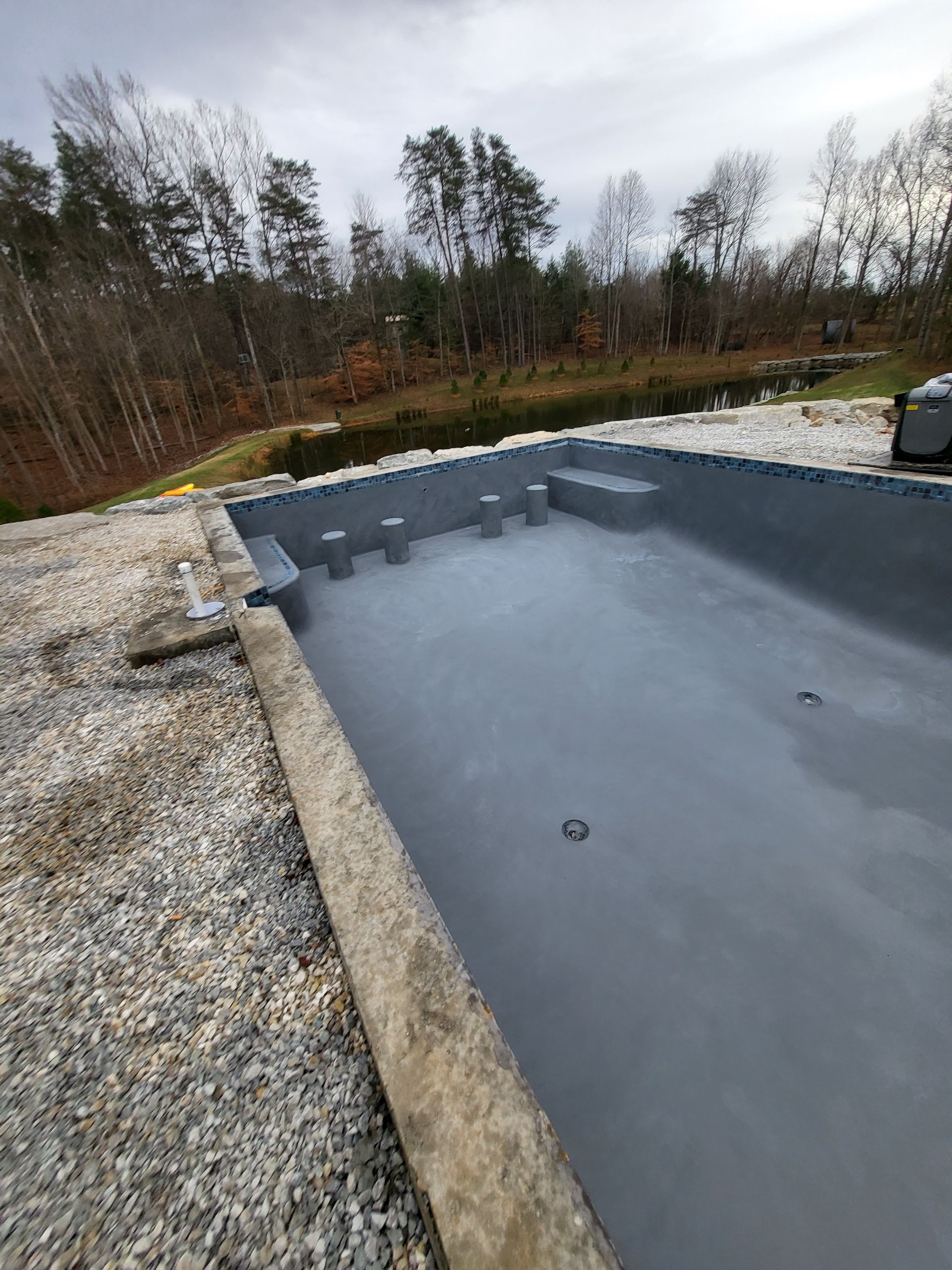 A large swimming pool is being built in the middle of a forest.