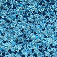 A close up of a swimming pool with blue water and black rocks.
