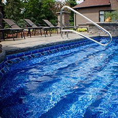 A swimming pool with blue tiles and a staircase leading to it.