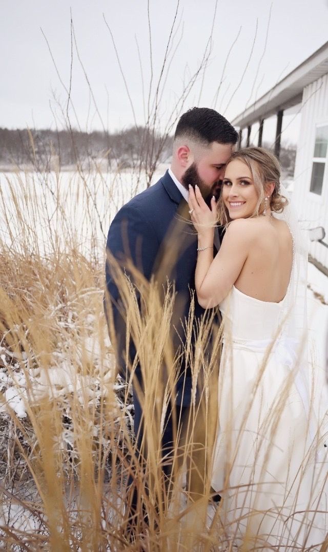 A bride and groom are posing for a picture in the snow.