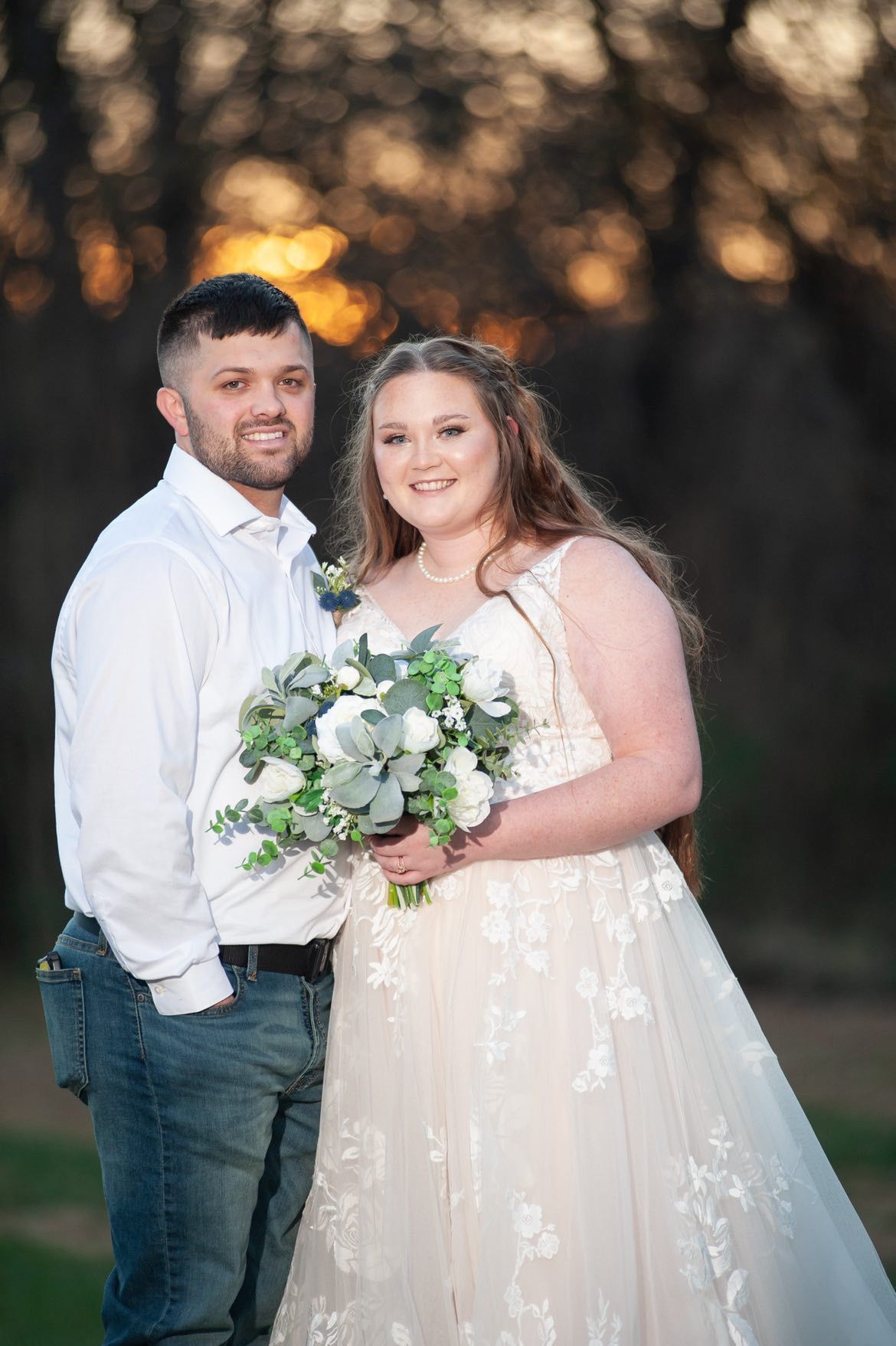 A bride and groom are posing for a picture while the bride is holding a bouquet of flowers.