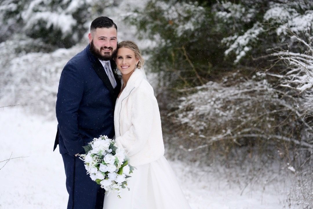 A bride and groom are posing for a picture in the snow.