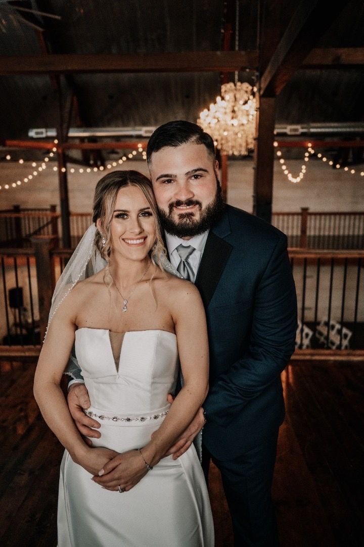 A bride and groom are posing for a picture in a barn.