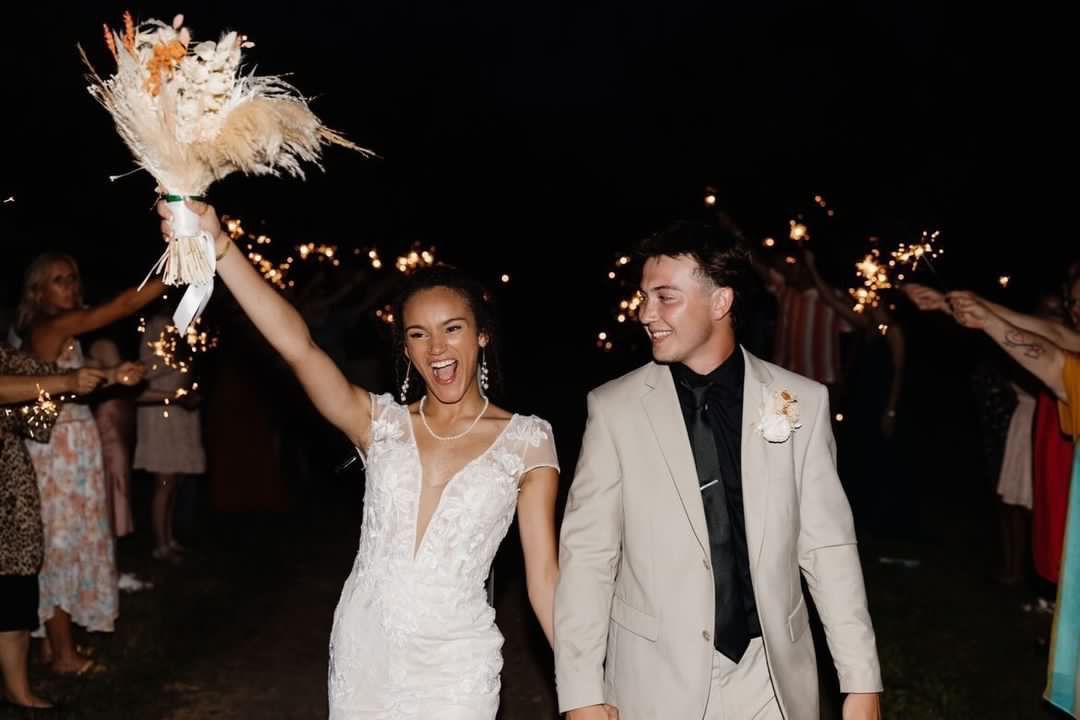 A bride and groom are walking through a tunnel of sparklers.