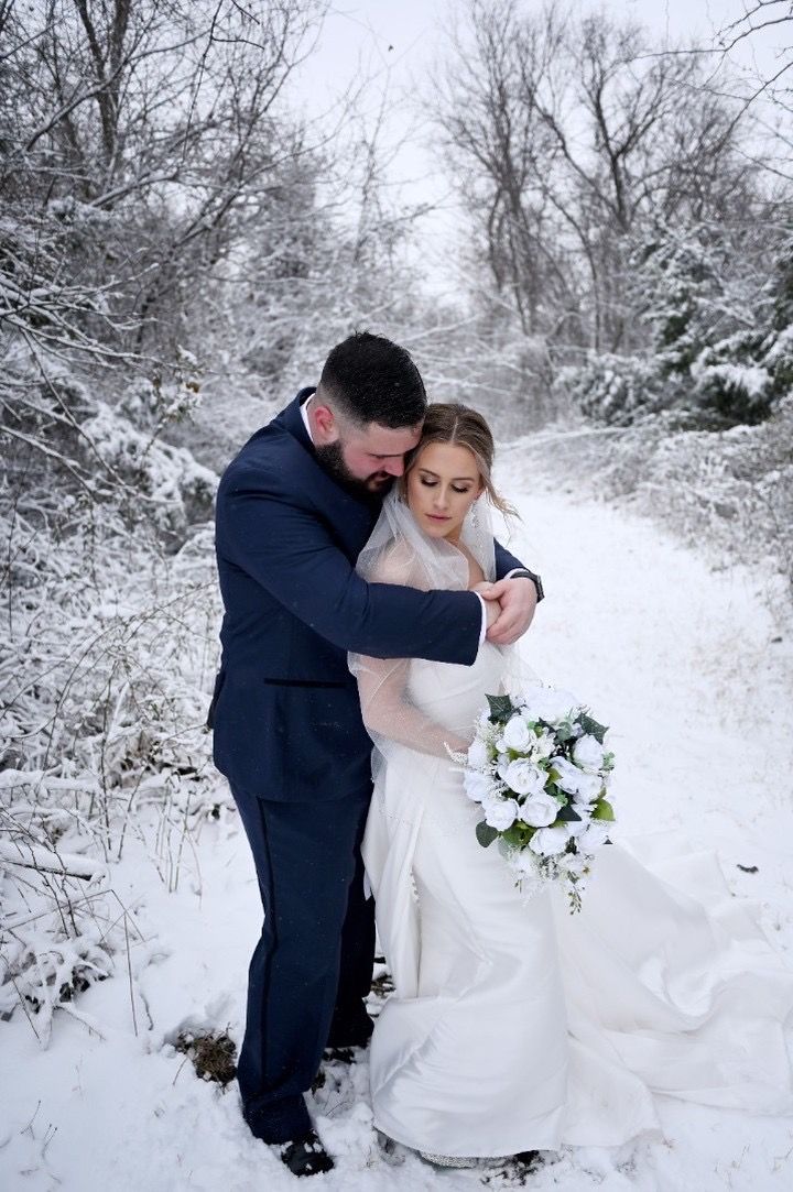 A bride and groom are posing for a picture in the snow.