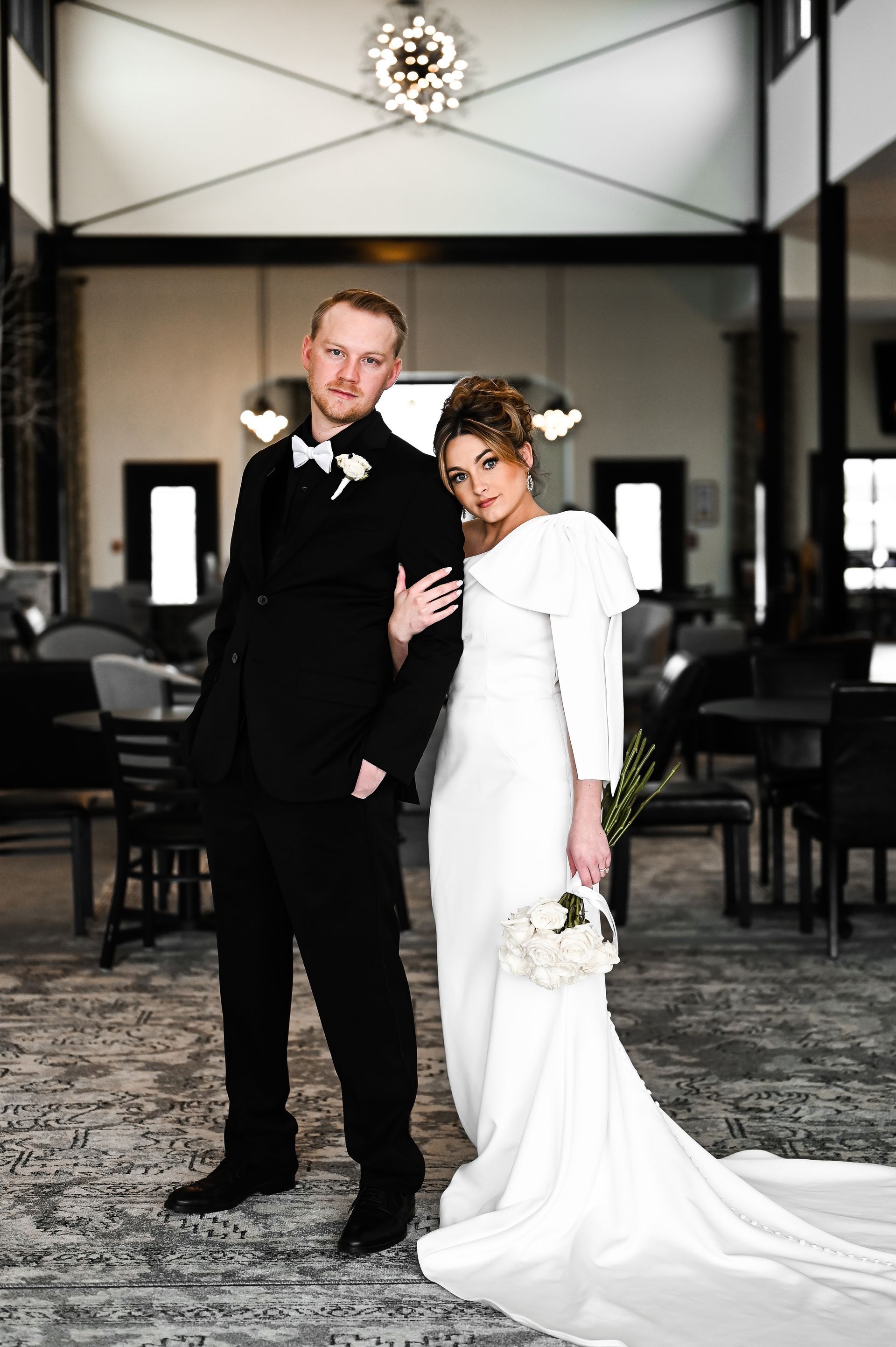A bride and groom are posing for a picture in a hotel lobby.
