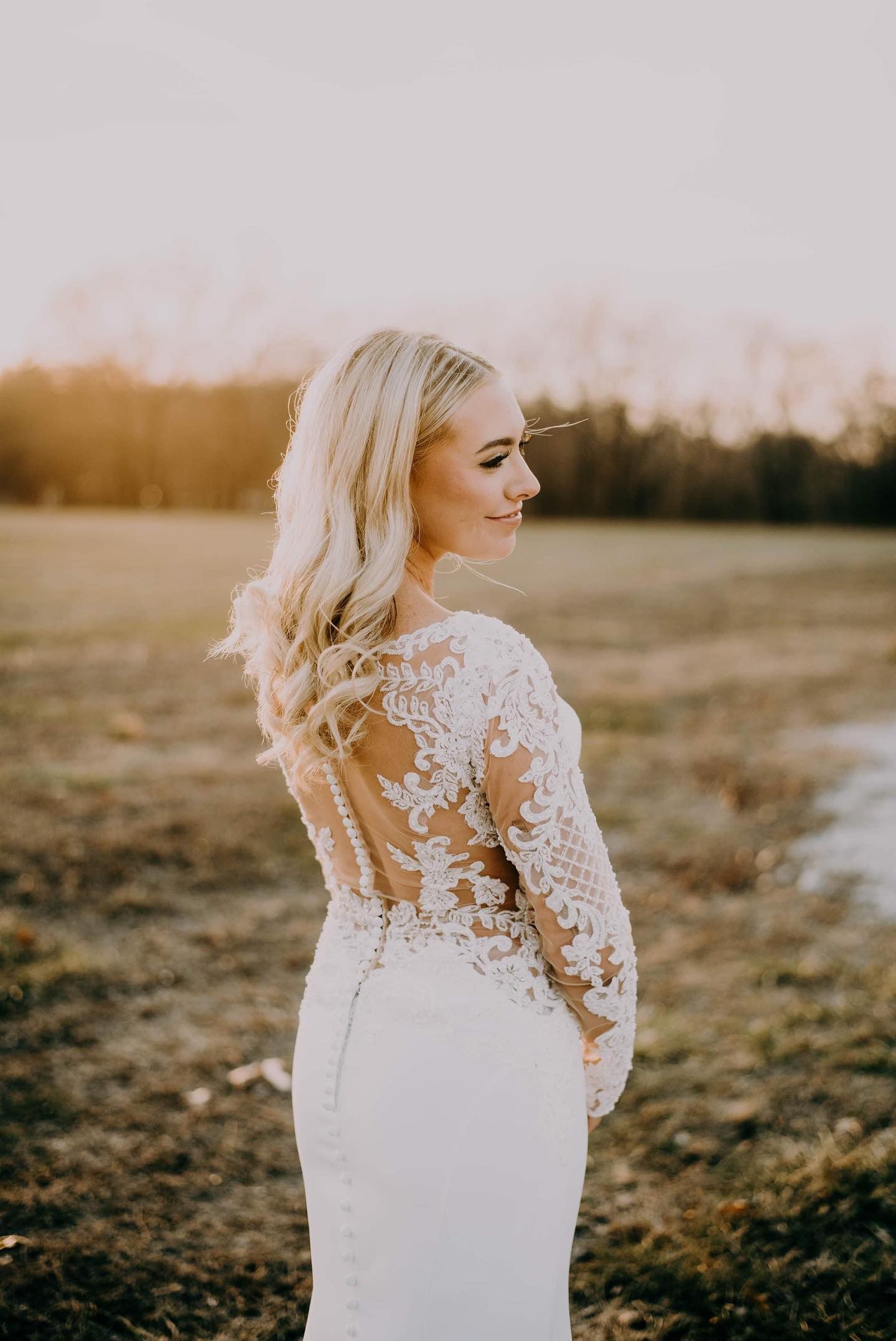 A woman in a wedding dress is standing in a field.