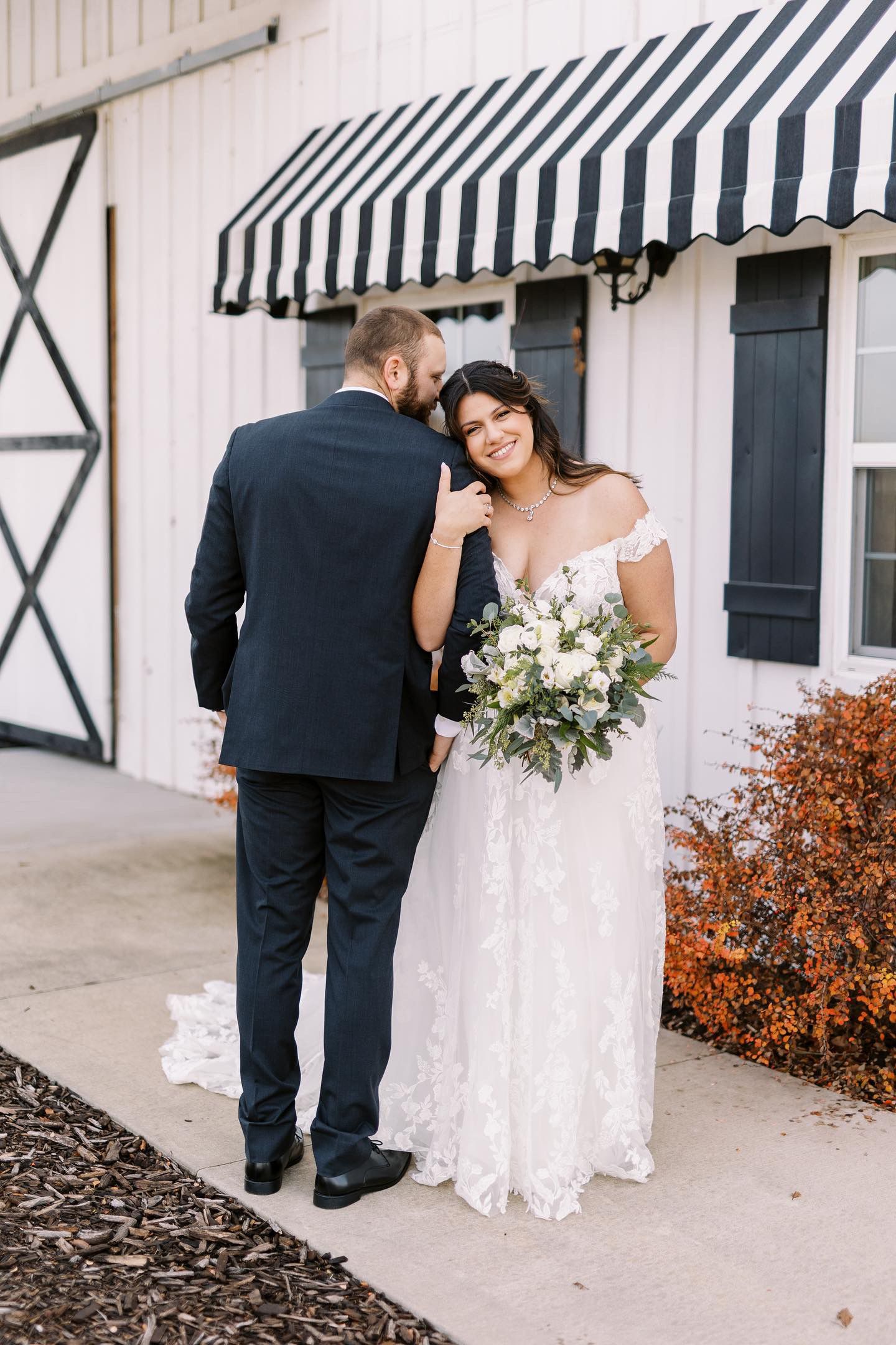 A bride and groom are posing for a picture in front of a white building.