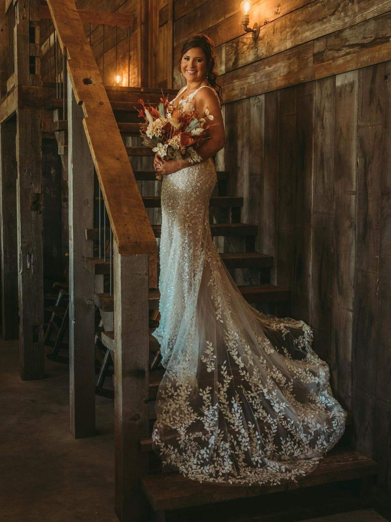 A bride in a wedding dress is standing on a set of stairs holding a bouquet of flowers.
